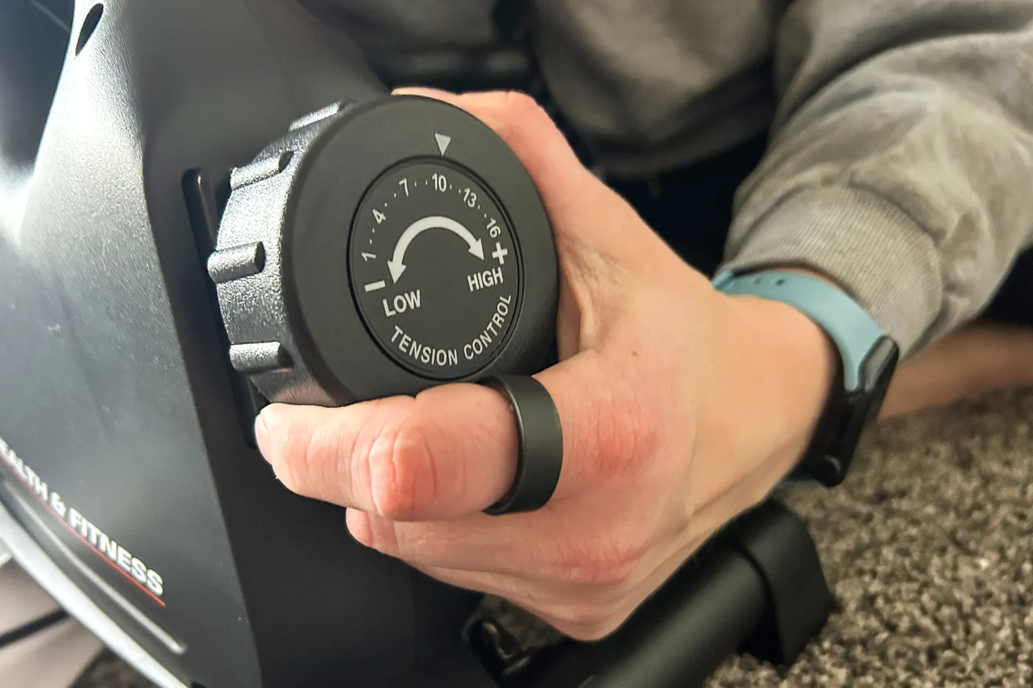 A person turns a dial on the side of the YOSUDA YBM-2 Under Desk Bike Pedal Exerciser