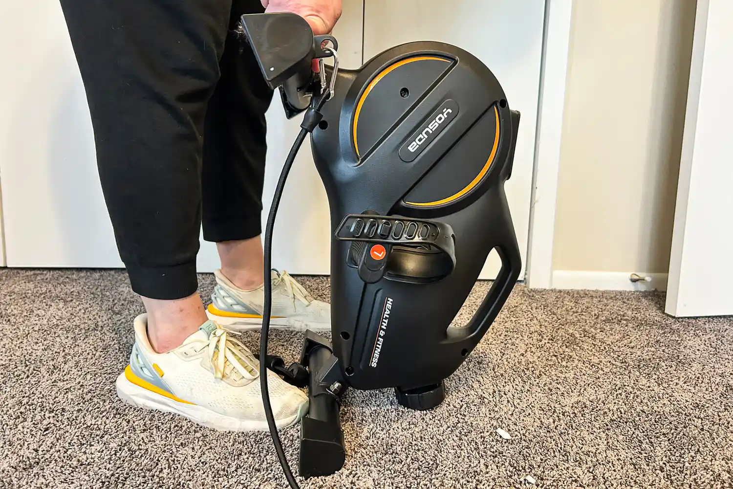 A person lifts the back of the YOSUDA YBM-2 Under Desk Bike Pedal Exerciser