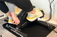 A person turns the tension dial on the YOSUDA YBM-2 Under Desk Bike Pedal Exerciser