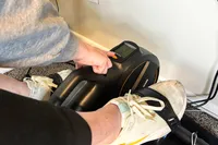 A person presses a button on the YOSUDA YBM-2 Under Desk Bike Pedal Exerciser