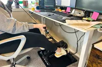 A person uses the arm bands on the YOSUDA YBM-2 Under Desk Bike Pedal Exerciser