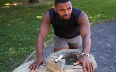 man leaning over drinking fountain feeling nauseated