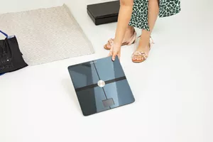 Person picking up Withings Body Comp Smart Scale from floor