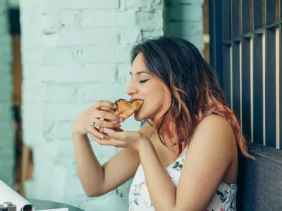 Woman eating croissant in coffee shop